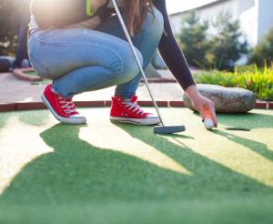 Junge Dame beim Minigolf Spielen