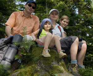 glückliche Familie rastet auf einem Stein beim Wandern