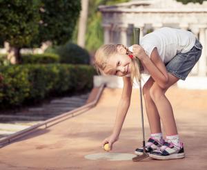 Ein Maedchen beim Minigolf Spielen