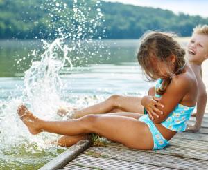 2 Kinder sitzen am Badesee